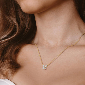 Close-up of a person wearing a butterfly gold necklace with a diamond pendant.