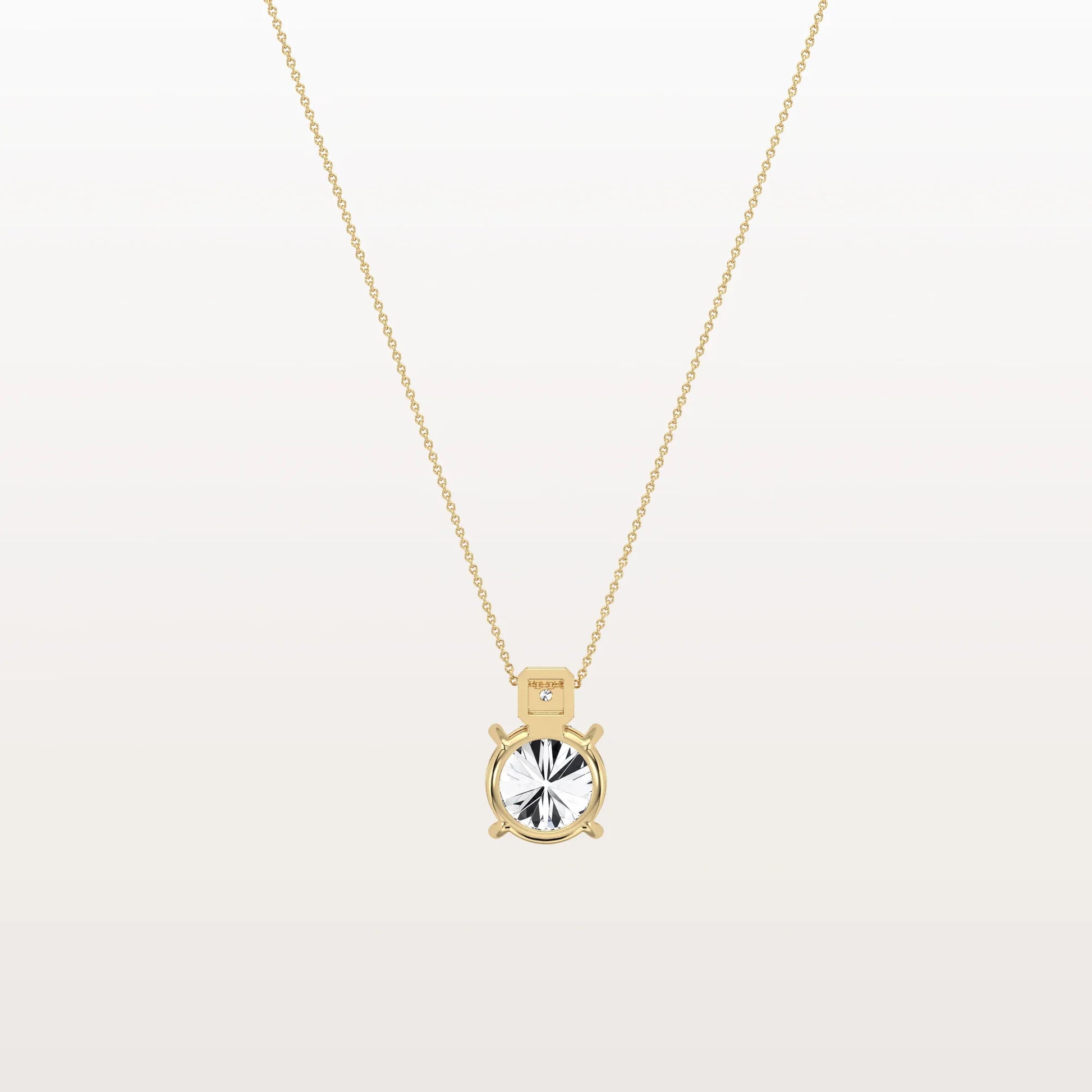 Gold necklace with a round pendant on a light gray background